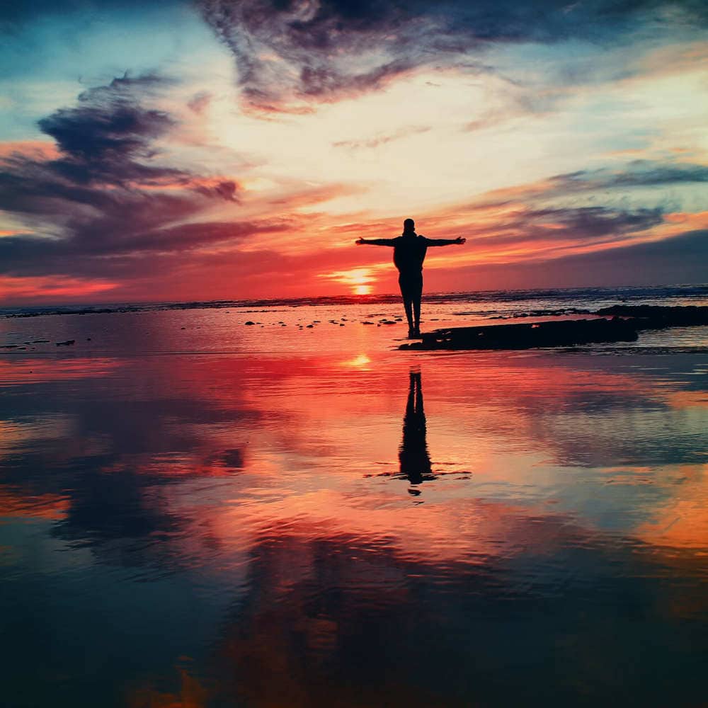 person standing on beach at sunset