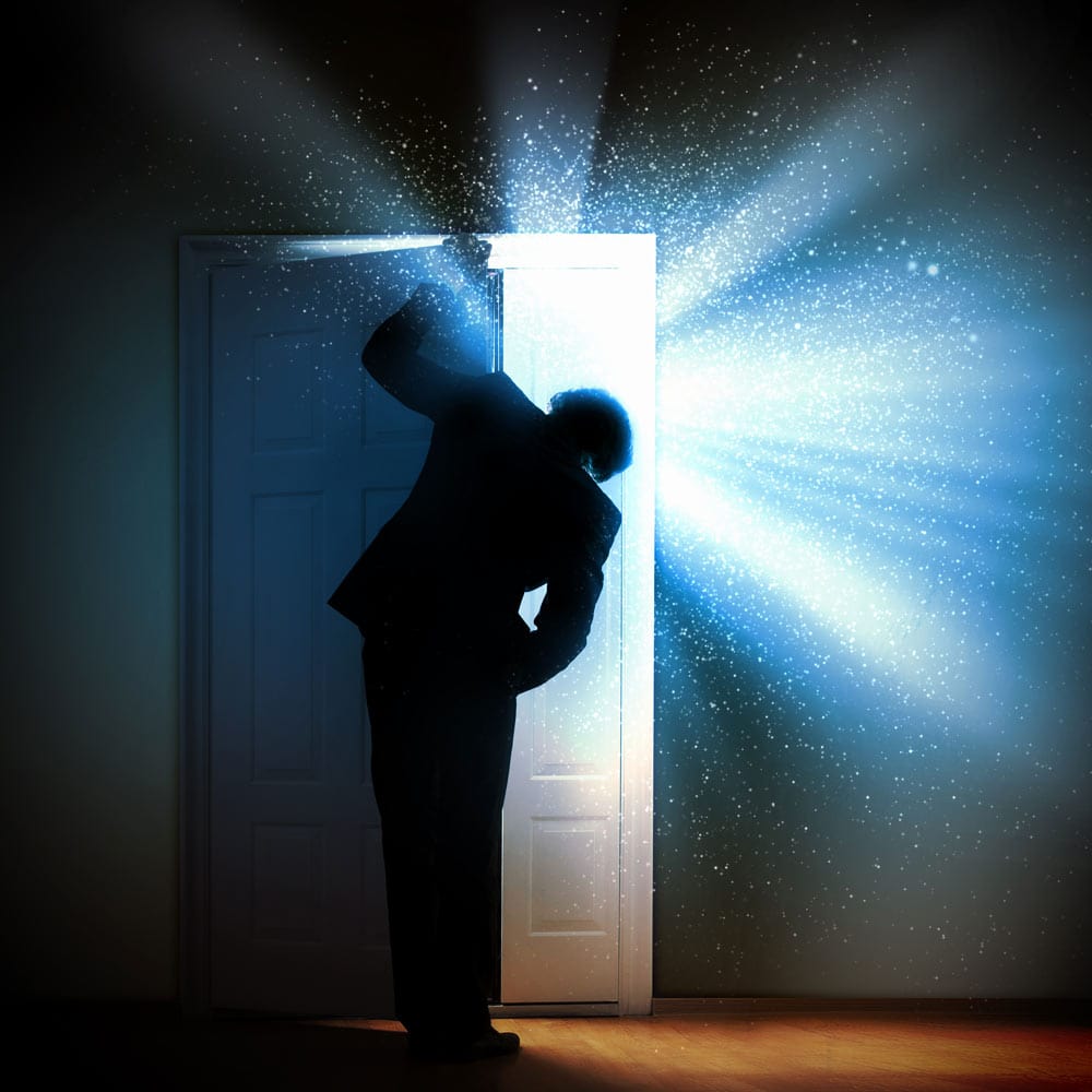 man in dark room looking out door to light